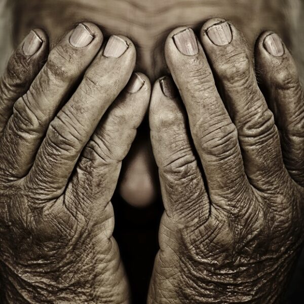 elderly woman's wrinkled hands cover her face in close-up, sepia tones - deposit photos